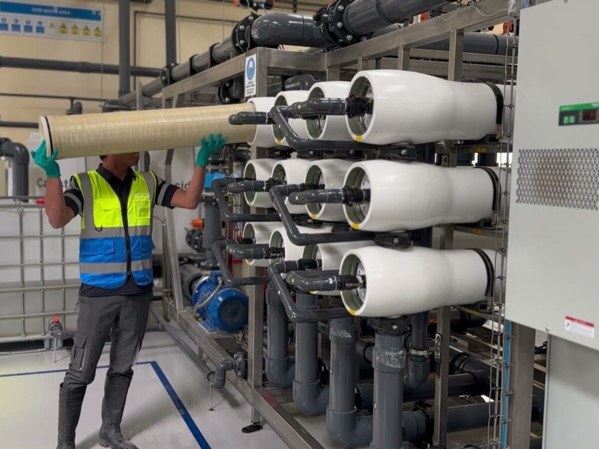 An operator in protective gear loading an element into a pressure vessel at the Second Life RO plant in Ras Al Khaimah